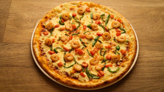 Shrimp, green pepper, and diced tomato pizza on a wooden board.