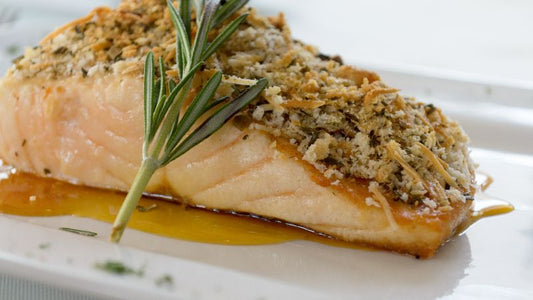 Herb-crusted salmon topped with breadcrumbs, garnished with rosemary, and served on a white plate.