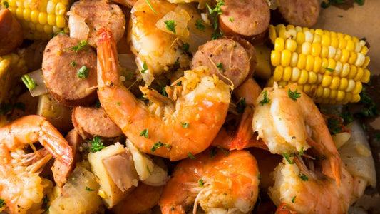 A close-up dish of shrimp, sausage slices, vegetables, and chopped herbs.