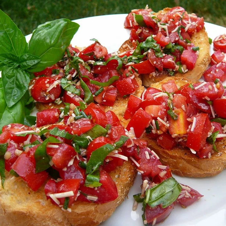 Bruschetta with diced tomatoes, basil, shredded cheese, and a fresh basil sprig.