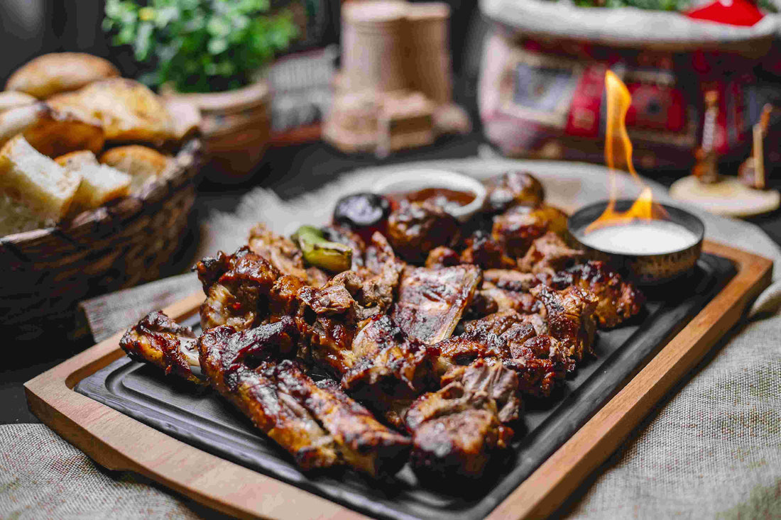 Grilled meat platter with dipping sauces, bread, and a lit candle.