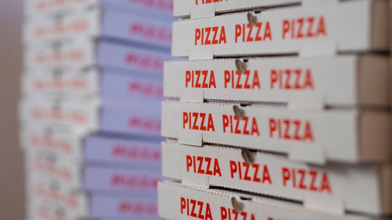 Pizza boxes stacked high with "PIZZA" printed in red on the sides.