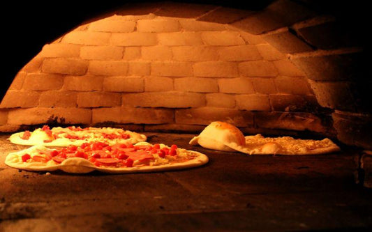 A pizza is being cooked in a brick oven.