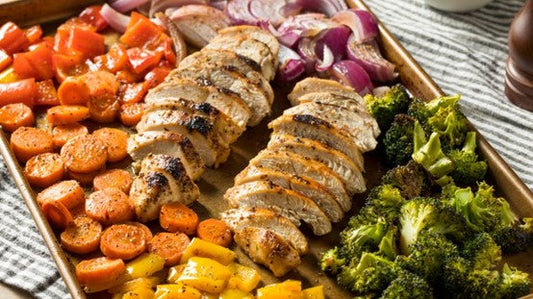 Sliced roasted chicken with carrots, red onions, bell peppers, and broccoli on a tray.