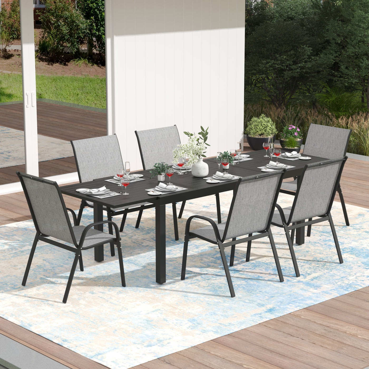 Outdoor dining set with a Pizzello Aluminum Patio Extendable Dining Table and six chairs on a patio.