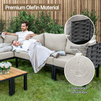 A couple lounges on a beige outdoor sectional with black armrests, waterproof fabric, and a Pizzello Propane Fire Pit Table.