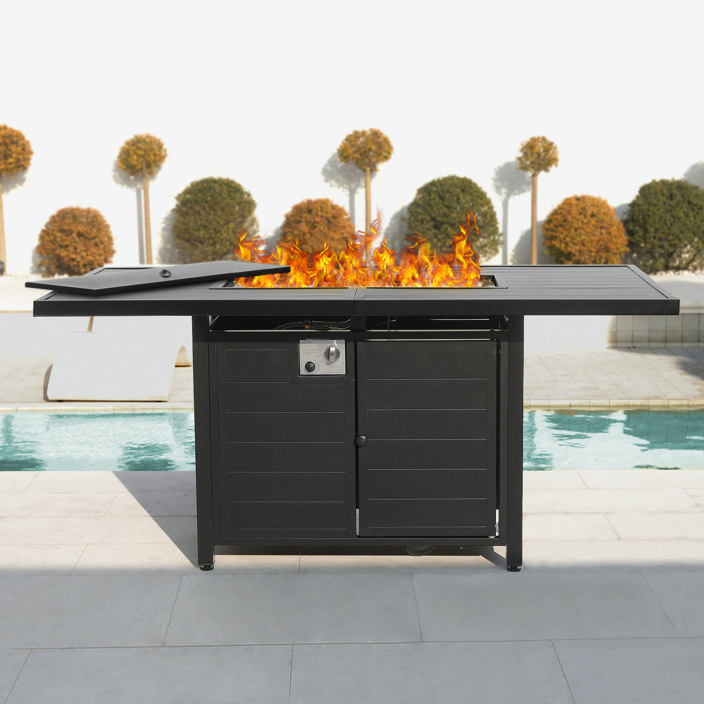 The Pizzello Passione 62.5" Fire Pit Table features a 50,000 BTU stainless steel burner, elegant black finish, and spacious tabletop near a pool.