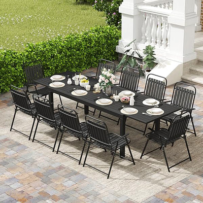 The Pizzello Aluminum Patio Extendable Dining Table has black chairs, plates, and floral centerpieces on a tiled patio. Rust-resistant finish.